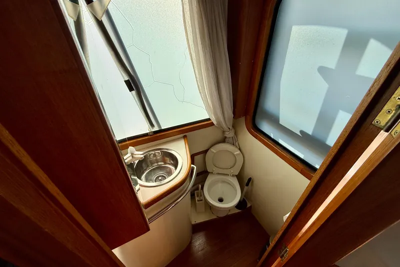 1990 Mikelson 42 yacht bathroom with sink, toilet, and frosted window.