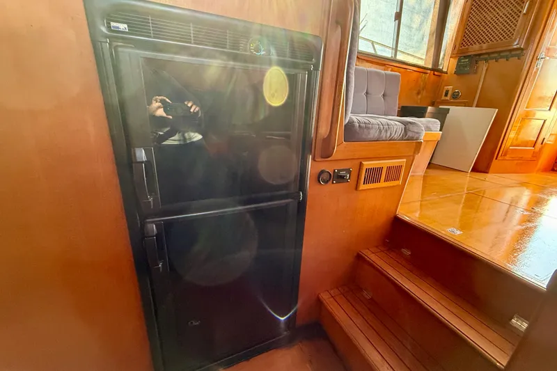 Interior of a 1990 Mikelson 42 yacht with a black refrigerator and wooden steps.