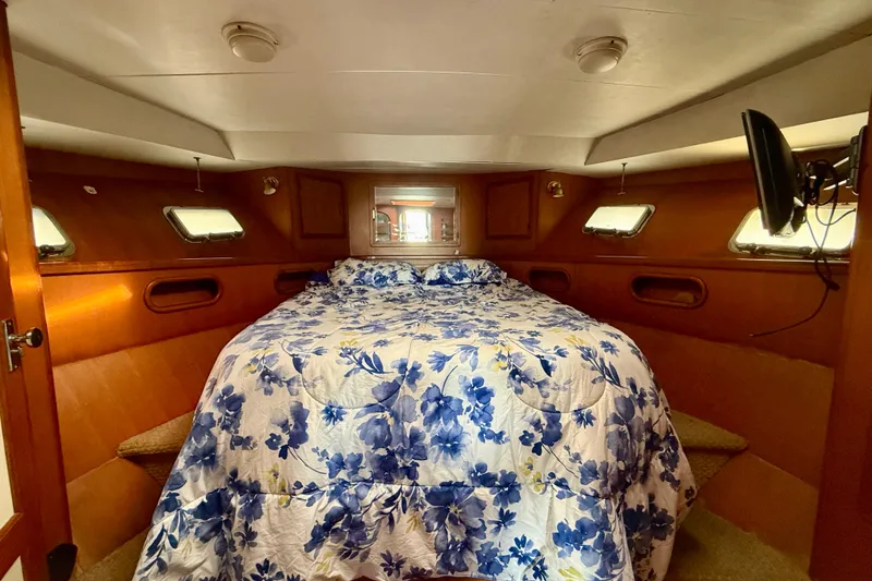 Cozy cabin interior of 1990 Mikelson 42 yacht with floral bedding and porthole windows.