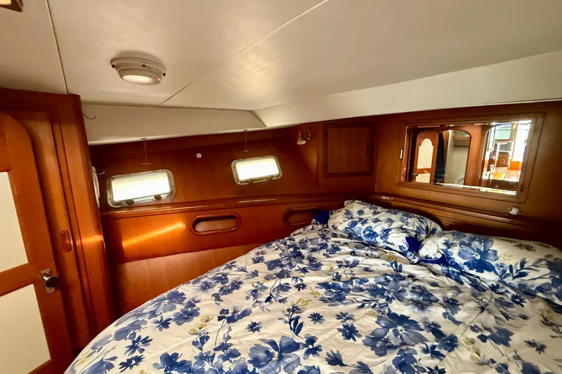 Cozy cabin interior of 1990 Mikelson 42 yacht with floral bedding and wooden accents.