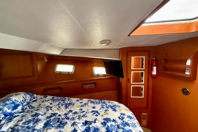 Cozy cabin interior of 1990 Mikelson 42 yacht with floral bedding and porthole windows.