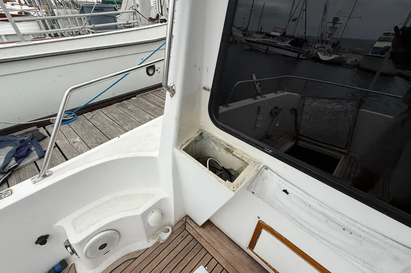 1990 Mikelson 42 yacht deck with open compartment, docked at marina.