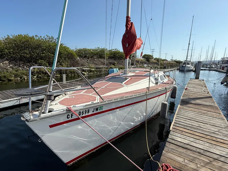 1989 Hunter 30 sailboat docked at marina, clear sky, calm water.