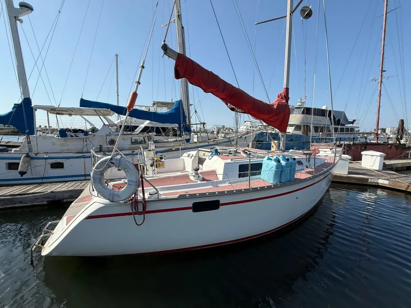1989 Hunter 30 sailboat docked at marina, featuring red sail cover and white hull.