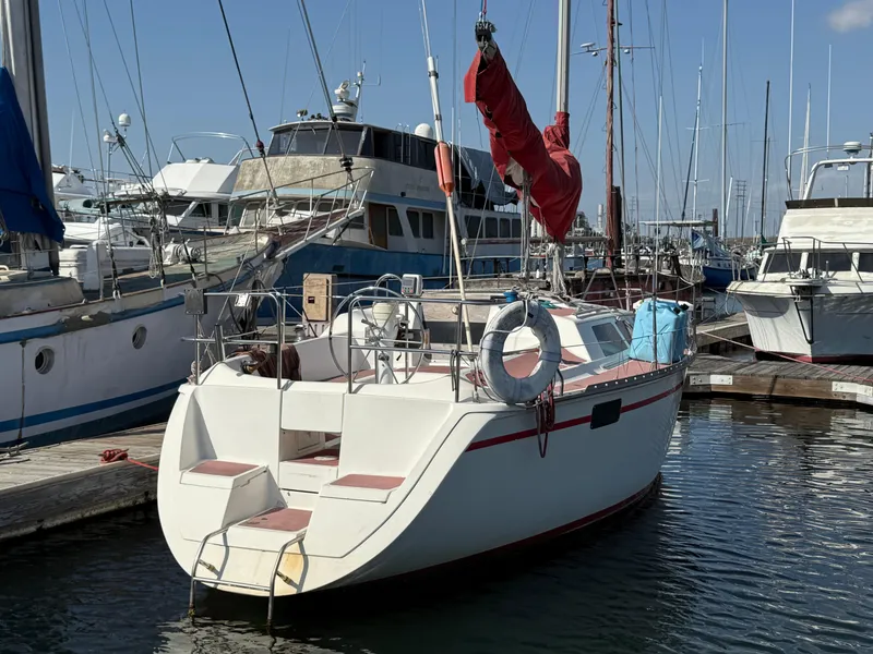 1989 Hunter 30 sailboat docked in marina, surrounded by other boats, clear sky.