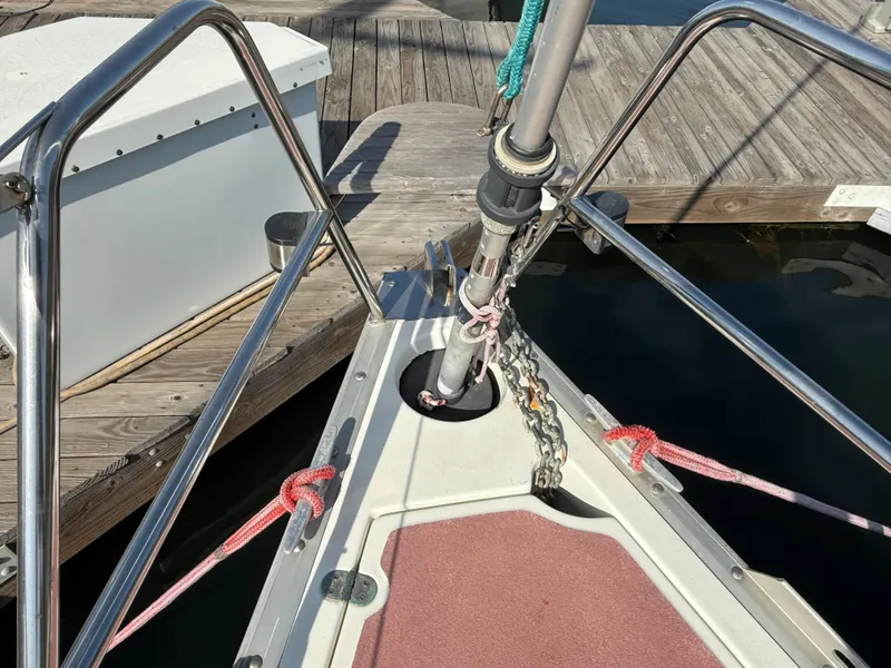 Bow of 1989 Hunter 30 sailboat docked, featuring stainless steel railings and anchor chain.