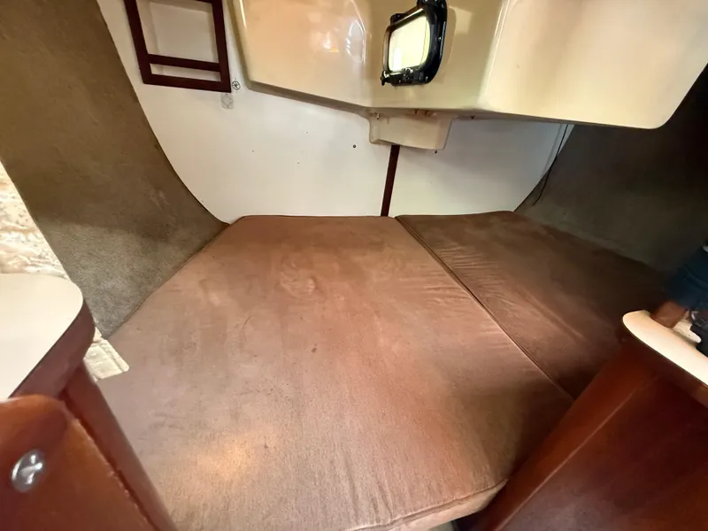 Cozy cabin interior of 1989 Hunter 30 sailboat with brown cushions and porthole.
