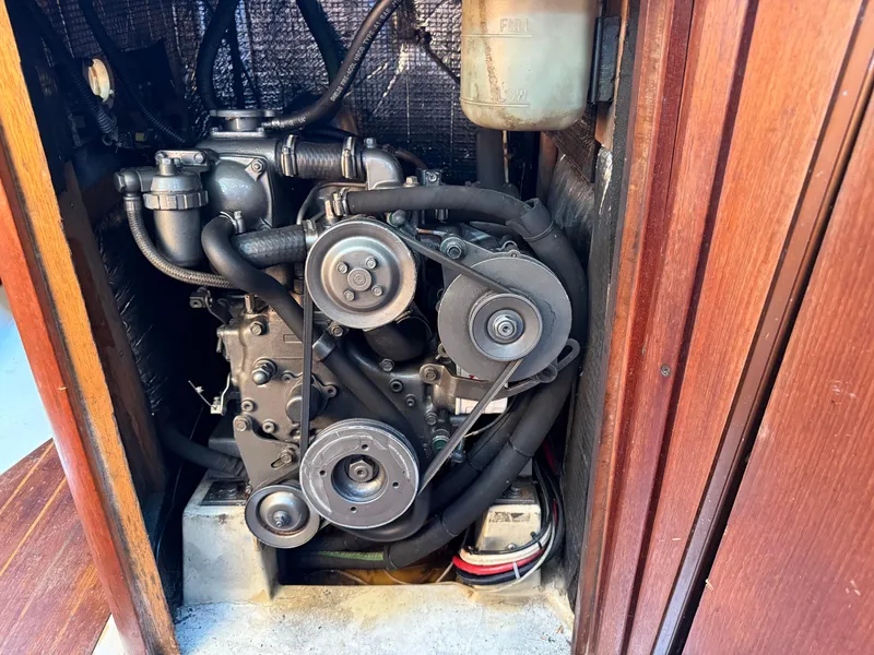 Engine compartment of a 1989 Hunter 30 sailboat, showcasing mechanical components and belts.