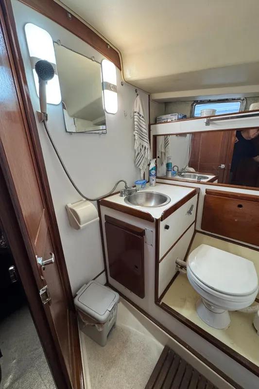 1981 Morgan 416 Out Island yacht bathroom with sink, toilet, mirror, and wooden accents.
