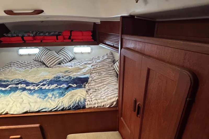 Cozy cabin interior of 1981 Morgan 416 Out Island sailboat with bed and wooden storage.