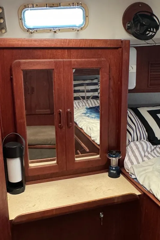 Interior of 1981 Morgan 416 Out Island yacht with wooden cabinetry and striped bedding.