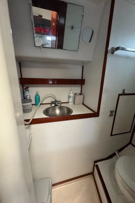 1981 Morgan 416 Out Island yacht bathroom with sink, mirror, and toiletries.