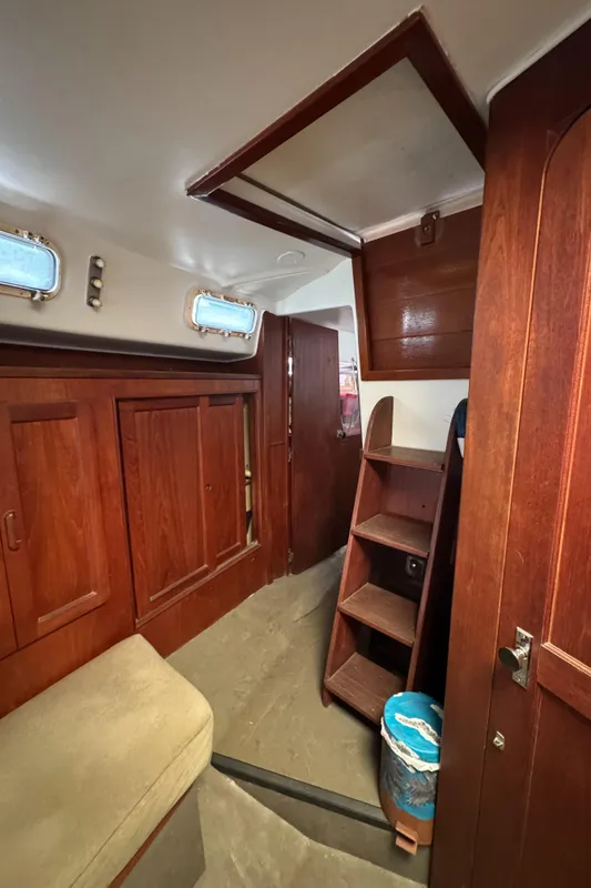 Interior of 1981 Morgan 416 Out Island sailboat with wooden cabinetry and ladder.