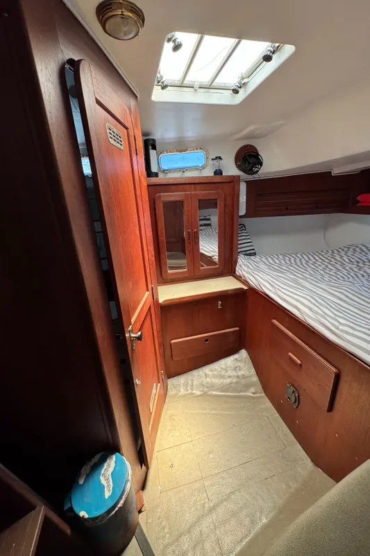 1981 Morgan 416 Out Island cabin interior with wood paneling and striped bedding.