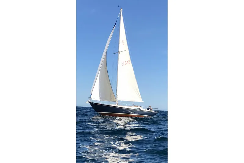 Sailing yacht Rhodes Bounty 1957 on open sea under clear blue sky.