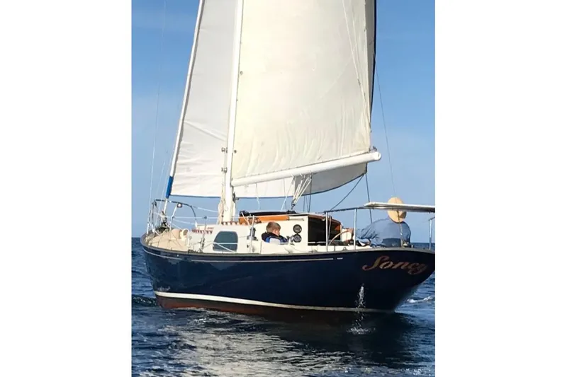 1957 Rhodes Bounty sailboat with white sails on open water.