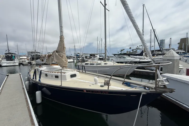1957 Rhodes Bounty sailboat docked at a marina, surrounded by other boats.
