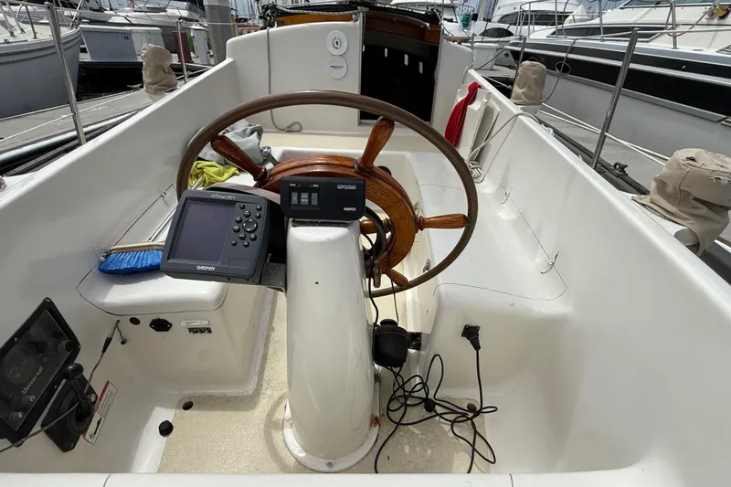 1957 Rhodes Bounty sailboat cockpit with wooden steering wheel and navigation equipment.