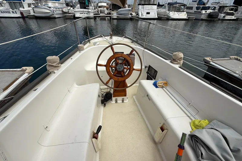 1957 Rhodes Bounty sailboat cockpit with wooden wheel, docked at marina.