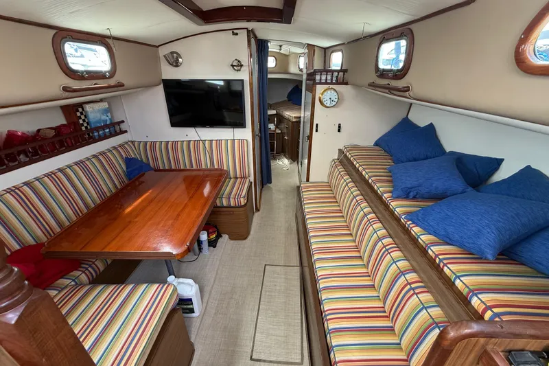 Interior of a 1957 Rhodes Bounty boat with striped seating and wooden table.