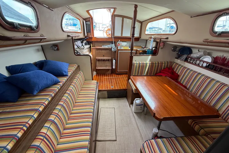 Cozy 1957 Rhodes Bounty boat interior with striped seating and wooden table.