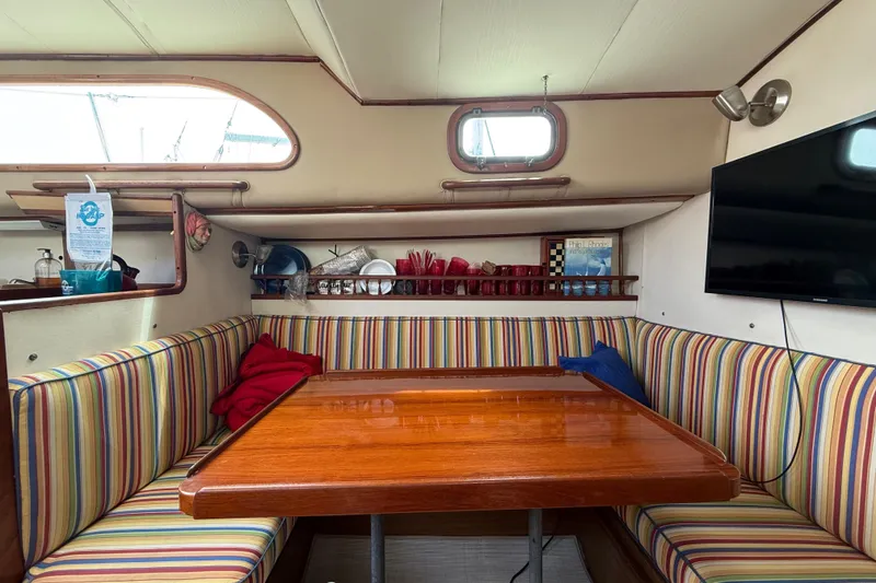 1957 Rhodes Bounty yacht interior with striped seating, wooden table, and wall-mounted TV.