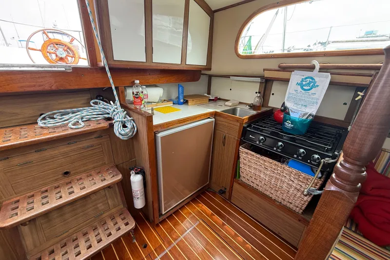 1957 Rhodes Bounty yacht interior with wooden cabinetry, stove, and compact kitchen area.