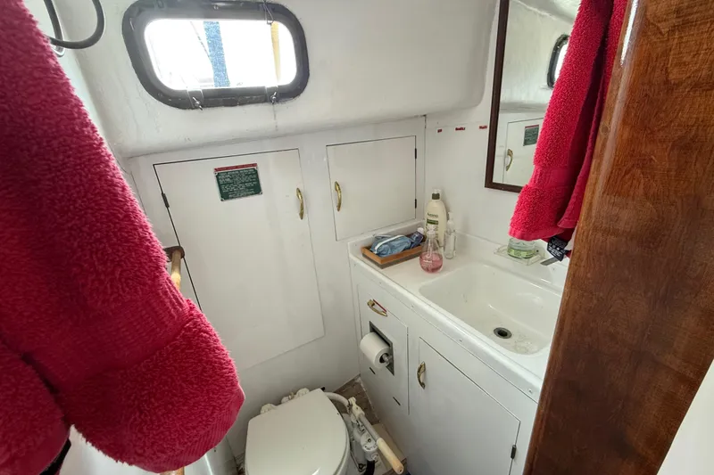 1957 Rhodes Bounty boat bathroom with sink, mirror, and red towels.