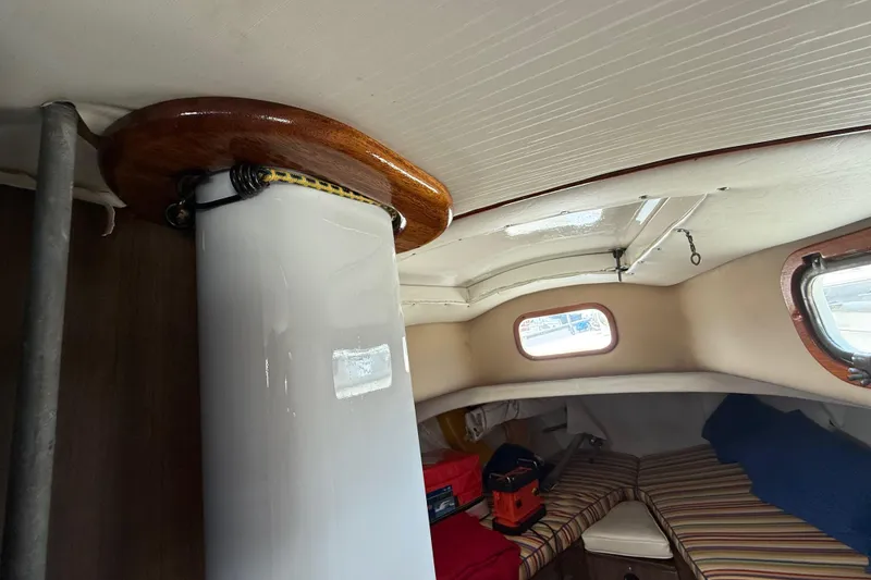 Interior of a 1957 Rhodes Bounty sailboat cabin with striped cushions and wooden accents.
