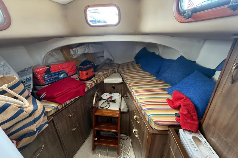 Cozy cabin interior of a 1957 Rhodes Bounty boat with striped cushions and storage.