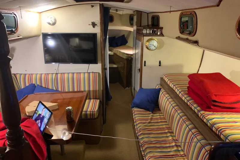 Interior of a 1957 Rhodes Bounty sailboat with striped seating and modern amenities.