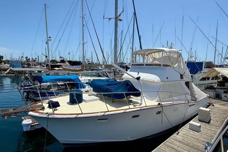 1971 Pacifica 44 Convertible yacht docked at marina, surrounded by sailboats under clear blue sky.