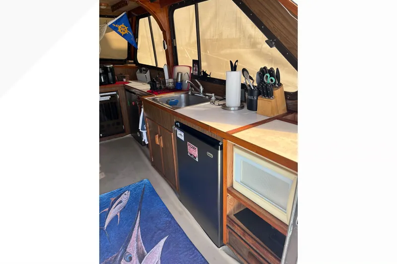 1971 Pacifica 44 Convertible boat interior with kitchenette, featuring sink, fridge, and utensils.