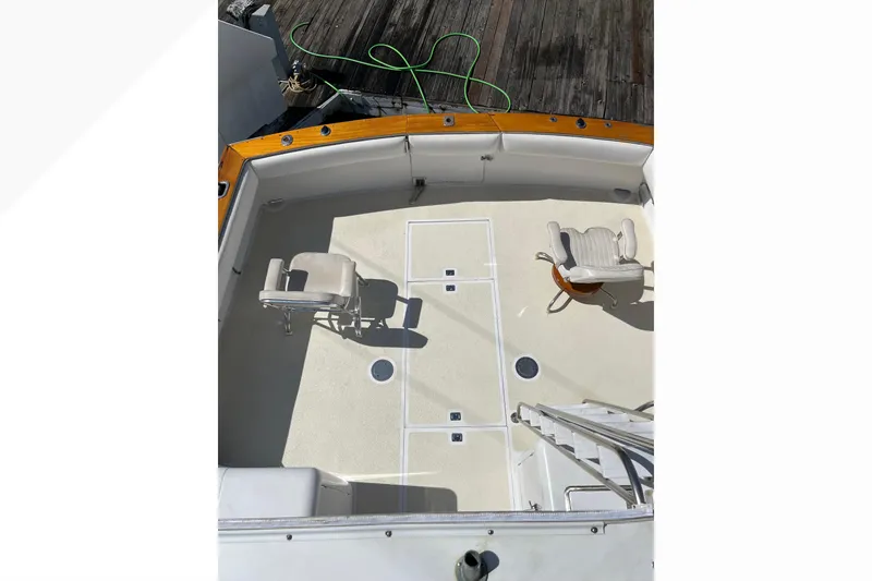 1971 Pacifica 44 Convertible boat deck with two chairs, wooden trim, and docked at a marina.