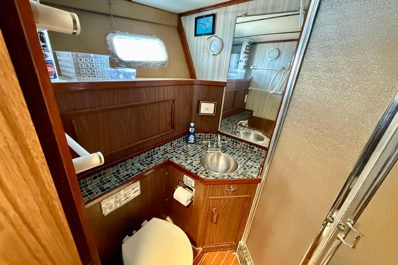 1971 Pacifica 44 Convertible yacht bathroom with wood paneling and mosaic countertop.