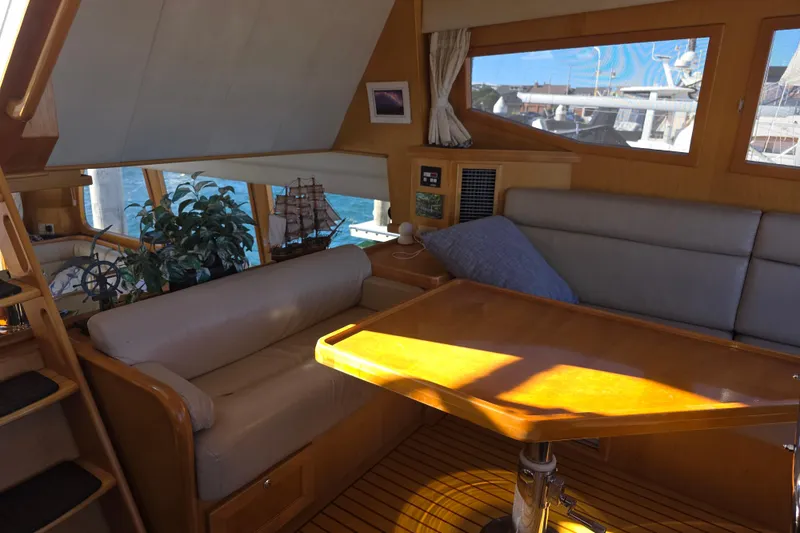 Interior of 2000 McKinna 48 Pilothouse yacht with cozy seating and wooden table.