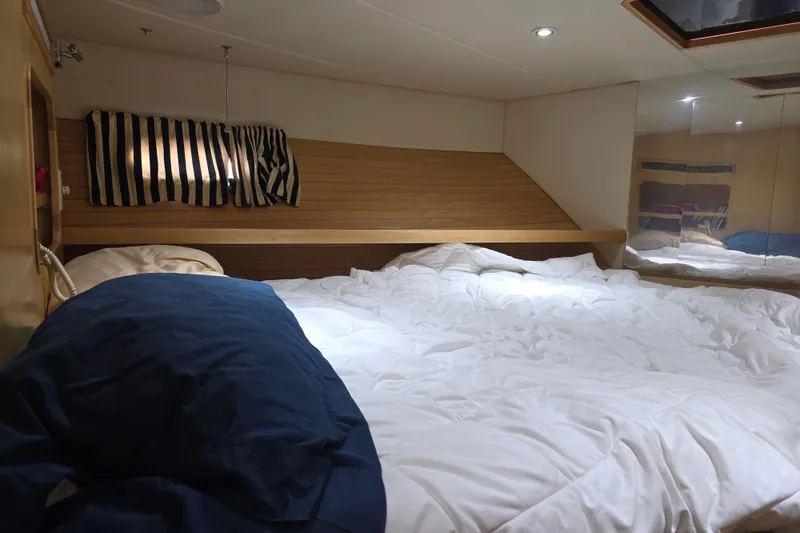 Cozy bedroom in 2000 McKinna 48 Pilothouse yacht with striped curtains and plush bedding.
