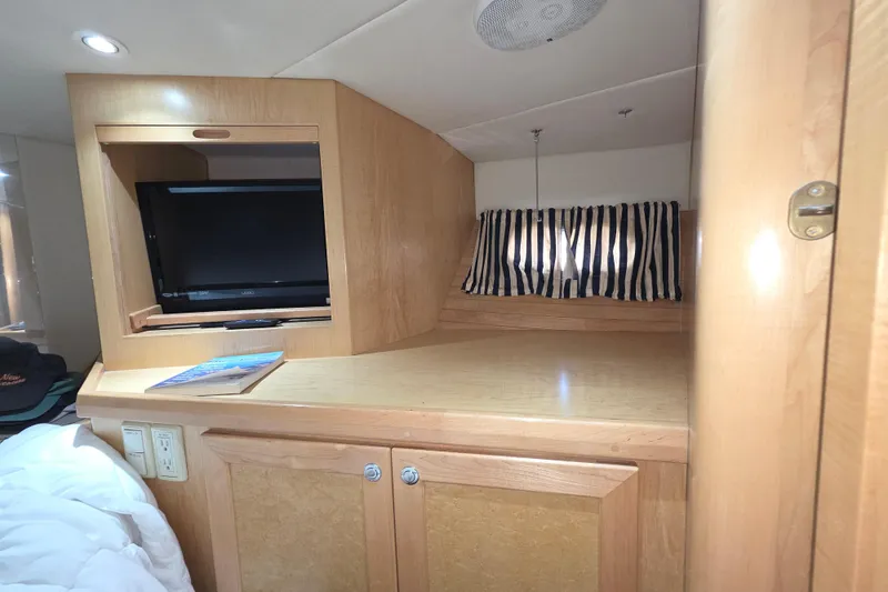 2000 McKinna 48 Pilothouse interior with TV, wooden cabinetry, and striped curtains.