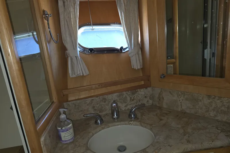 Bathroom interior of 2000 McKinna 48 Pilothouse yacht with marble countertop and porthole window.