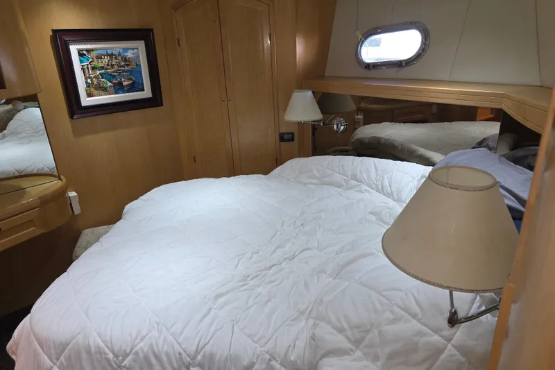 Cozy bedroom in 2000 McKinna 48 Pilothouse yacht with framed artwork and porthole window.