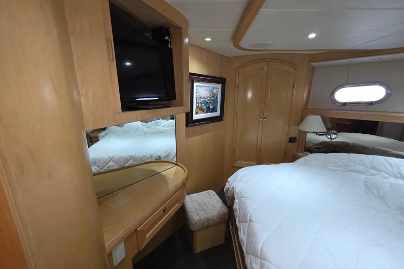 Luxurious cabin interior of 2000 McKinna 48 Pilothouse yacht with cozy bed and TV.