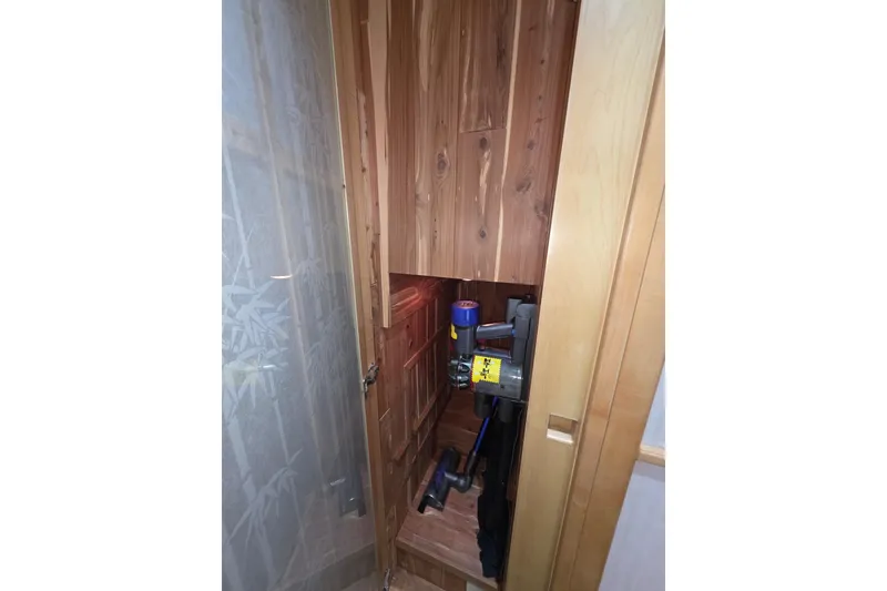 Wooden storage compartment on 2000 McKinna 48 Pilothouse, housing a vacuum cleaner.