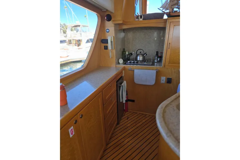 Interior of 2000 McKinna 48 Pilothouse yacht kitchen with wooden cabinetry and appliances.