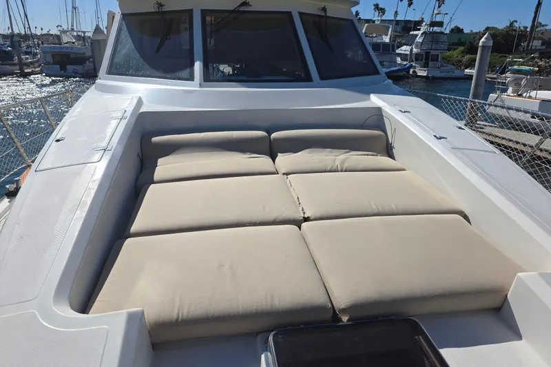 Luxurious sunbathing area on a 2000 McKinna 48 Pilothouse yacht in a marina.