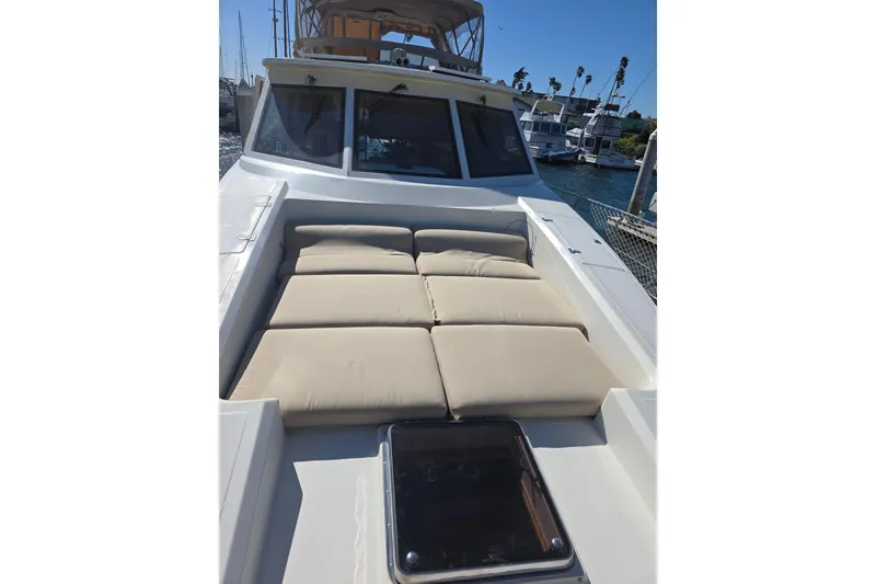 2000 McKinna 48 Pilothouse yacht with beige sun pads on deck, docked in marina.