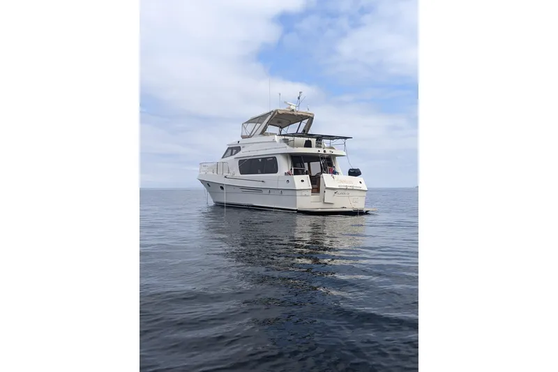 2000 McKinna 48 Pilothouse yacht on calm ocean waters under a cloudy sky.