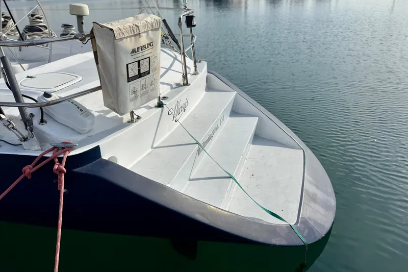 1985 MacGregor 65 sailboat stern with lifebuoy, docked on calm water.