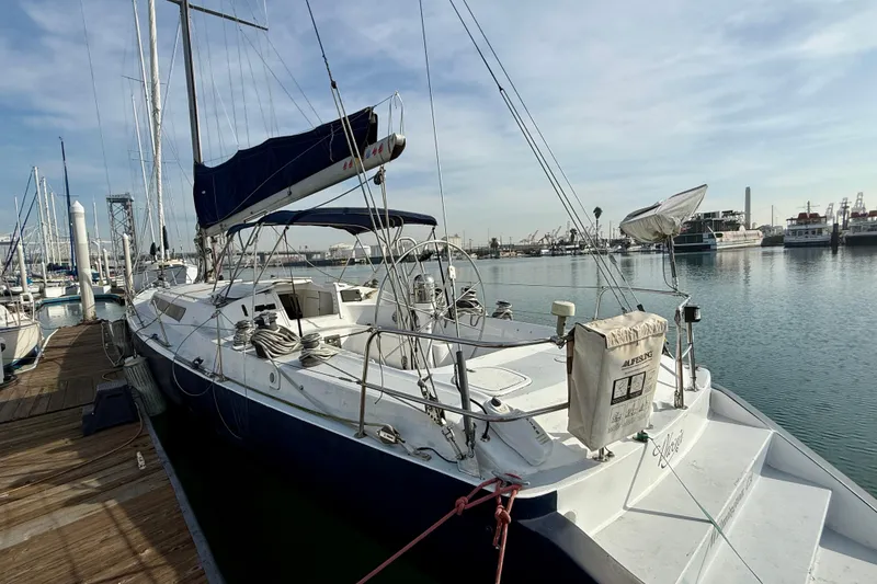 1985 MacGregor 65 sailboat docked at marina, clear sky, calm water.