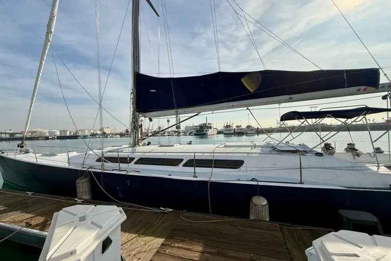 1985 MacGregor 65 sailboat docked at a marina, featuring a sleek design and blue hull.
