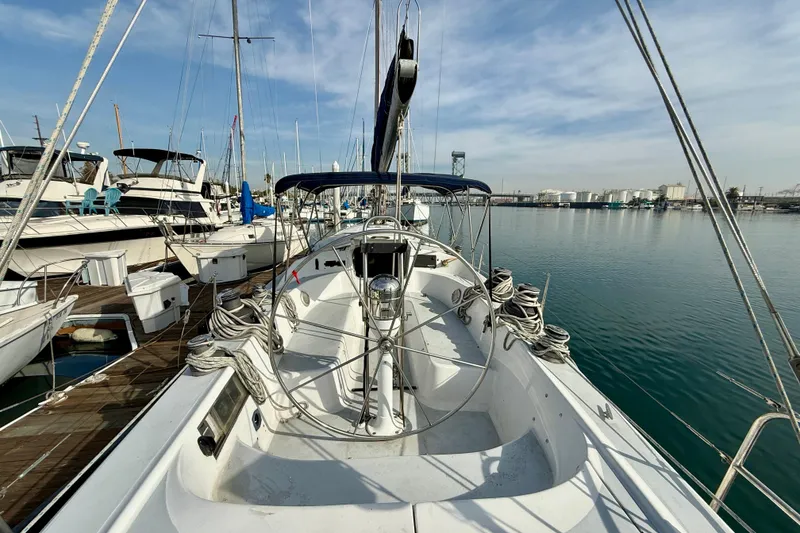1985 MacGregor 65 sailboat docked in a marina, surrounded by other boats.
